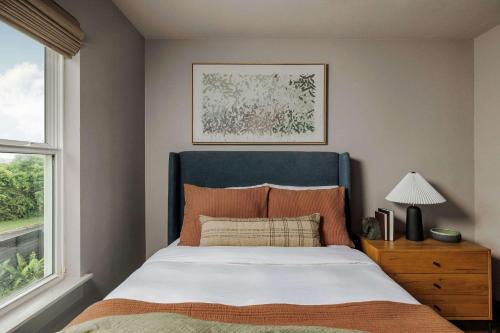a bedroom with a bed with a blue headboard and a window at Modern Designer Home with Shared Pool in Austin