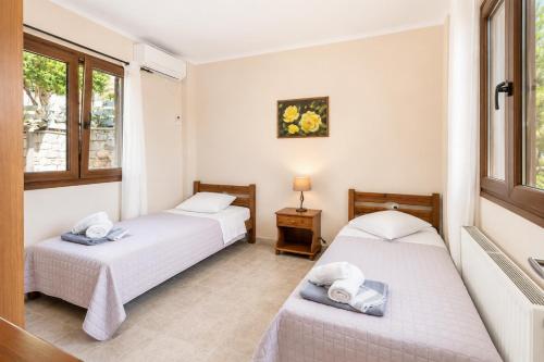two beds in a room with two windows at Villa Elpida in Gaios