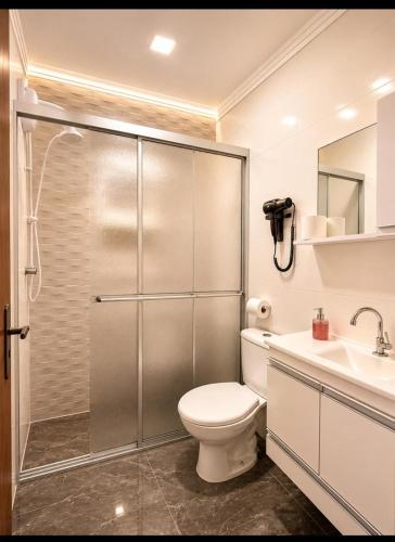 a bathroom with a shower and a toilet and a sink at Roupa cama Wi-Fi garagem ar Cond beira mar 50 m in Tramandaí