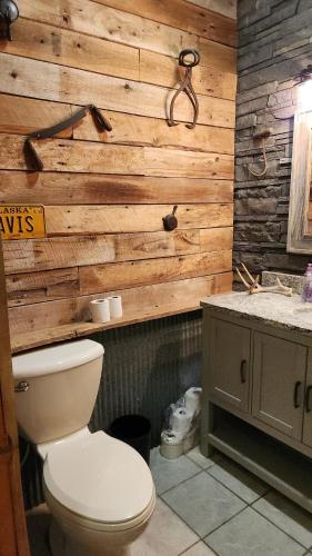 a bathroom with a toilet and a wooden wall at The Cabin at Solitude Junction in Opdyke