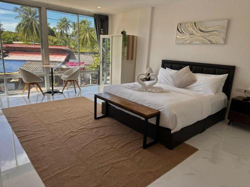 ein Schlafzimmer mit einem Bett mit einem Tisch und einem Balkon in der Unterkunft Keya hotel samui in Plai Laem