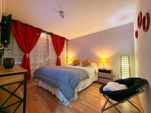 a bedroom with a bed with red curtains and a chair at Departamentos Innova in Copiapó