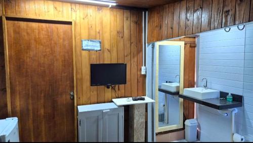 a bathroom with two sinks and a tv on the wall at Pousada Vino & Leta O seu parador no centro in Grão Pará