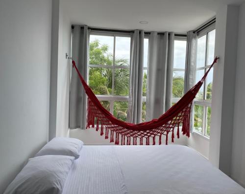a bed in a bedroom with a hammock in a window at Hotel La Cima in Arboletes