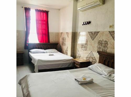 a bedroom with two beds and a red window at Hotel La Palma Girardot in Girardot