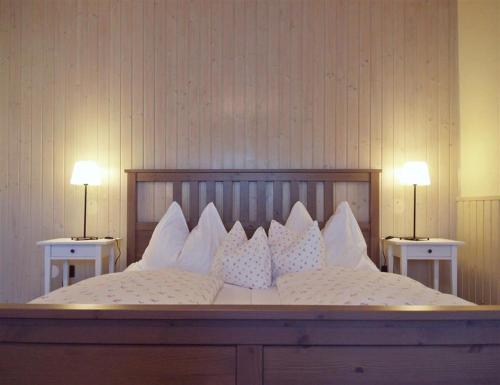 uma cama grande com almofadas brancas em cima em Huber Panzió em Fertőrákos
