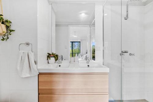 a white bathroom with a sink and a shower at Pacific Place Apartments in Gold Coast
