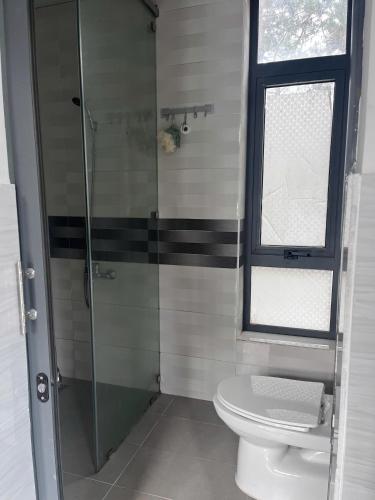 a bathroom with a toilet and a glass shower at Mây Măng Đen Villa in Chương Nghĩa