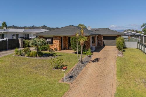 a house with a brick driveway in front of a yard at Family Friendly-Whitianga in Whitianga