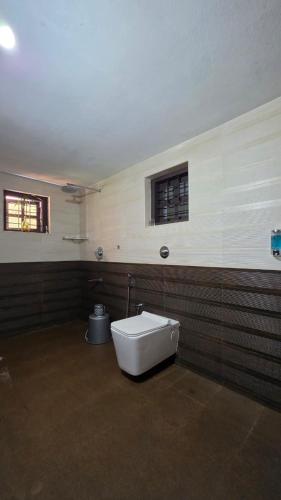 a bathroom with a toilet and a window on the wall at Coffeehut Pool Villa in Pinangode