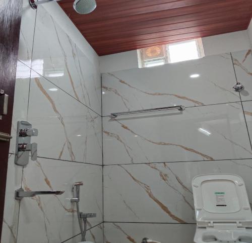 a bathroom with a marble shower stall with a phone at Annai Ocean Park in Velankanni