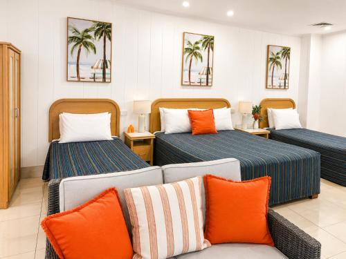 a hotel room with two beds and a couch at Chelsea Motor Inn in Coffs Harbour