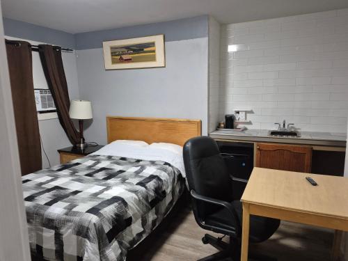 a hotel room with a bed and a desk and a sink at Park Side Motel in Peterborough