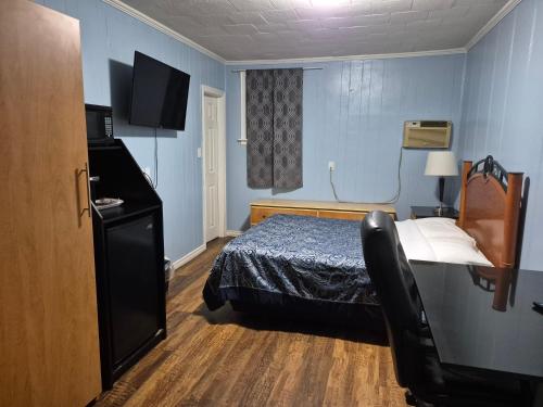 a hotel room with a bed and a desk with a television at Park Side Motel in Peterborough