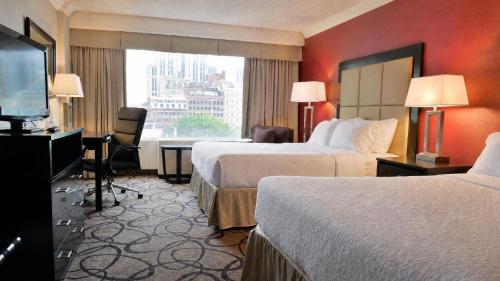 a hotel room with two beds and a flat screen tv at Holiday Inn Montreal Centre Ville Downtown by IHG in Montreal