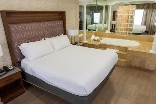 a bedroom with a bed and a bathroom with a tub at Holiday Inn Plainview-Long Island by IHG in Plainview