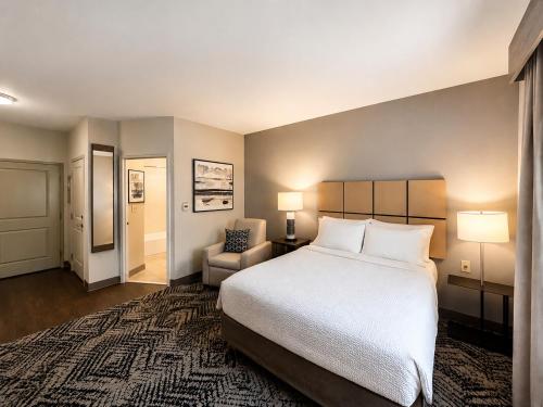 a hotel room with a bed and a chair at Candlewood Suites Auburn by IHG in Auburn