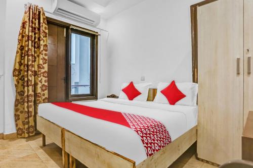 a bedroom with a bed with red pillows and a window at Hotel O Premium Inn in New Delhi