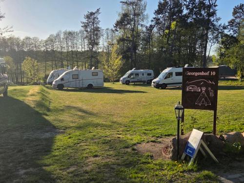 a sign in the grass next to a group of rvs at Stellplatz für VAN & Wohnmobile in Carpin