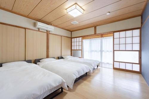 three beds in a room with wooden walls and windows at Shima Yadori Nagomi in Oshima