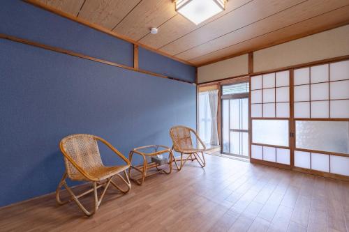 a room with three chairs and a table and windows at Shima Yadori Nagomi in Oshima