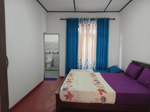 a bedroom with a bed with purple sheets and blue curtains at NIVRA Homestay in Kumbalwela
