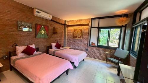 a room with two beds and a chair in it at SuanGlangNa in Phrae