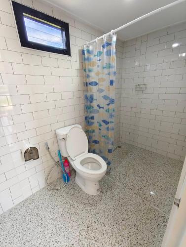 a bathroom with a toilet and a shower curtain at บ้านนอร์ดิก เฮาส์ เขาค้อ in Khao Kho