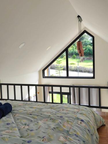 a bedroom with a bed and a large window at บ้านนอร์ดิก เฮาส์ เขาค้อ in Khao Kho