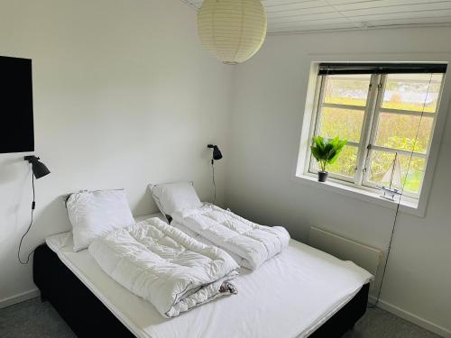 a bedroom with two beds with white sheets and a window at Lovely Cottage With Secluded Garden in Rødby