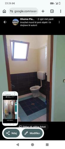 a picture of a bathroom with a toilet and a cell phone at Vila Gega in Tale