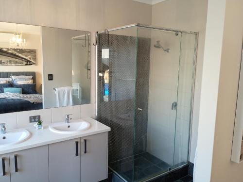 a bathroom with two sinks and a glass shower at Eden beach retreat in Jindalee