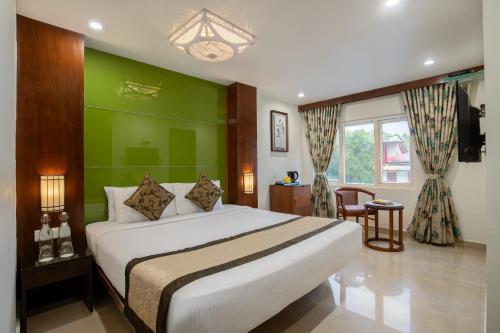 a bedroom with a bed and a green wall at TSG Emerald View Hotel and SPA in Port Blair