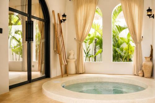 a bathroom with a large tub in a room with windows at Ôkeanos Boutique Hotel - Uluwatu Ungasan in Uluwatu