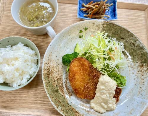 a plate of food with rice and broccoli on a table at あらとんとんの宿 in Setouchi