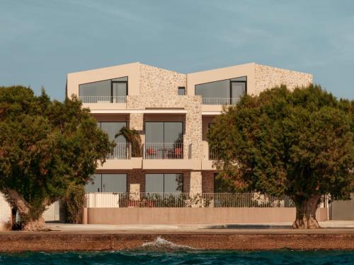 a building with trees in front of it at Petra Mare Villas in Psathopyrgos