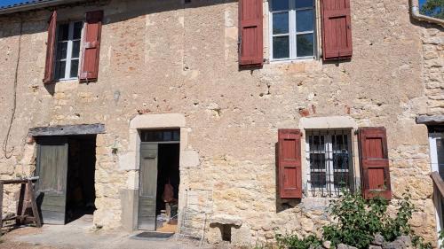 an old stone building with red shutters and a door at Au soleil in Virac