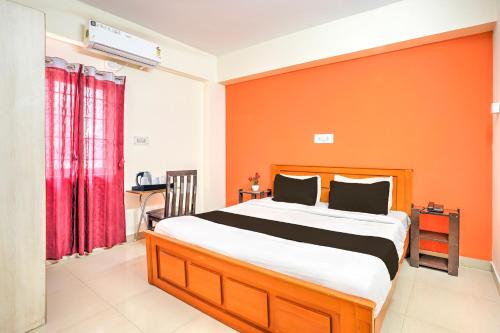 a bedroom with a large bed with an orange wall at Collection O Kadugodi Tree Park Metro Station Bengaluru Formerly Royal Rooms in Bangalore