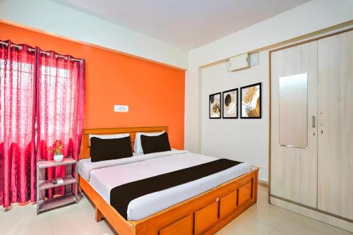 a bedroom with a bed with an orange wall at Collection O Kadugodi Tree Park Metro Station Bengaluru Formerly Royal Rooms in Bangalore