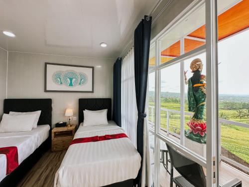 two beds in a room with a window at Bhuana Agung Villa and Restaurant in Jatiluwih