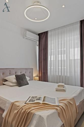 a bedroom with a large bed with a book on it at Apartment in MoonLight Residence in Mamaia