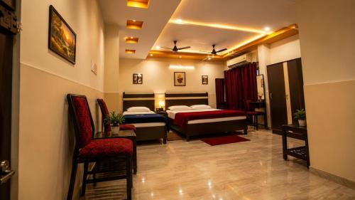 a hotel room with two beds and a chair at M R Hotels in Visakhapatnam