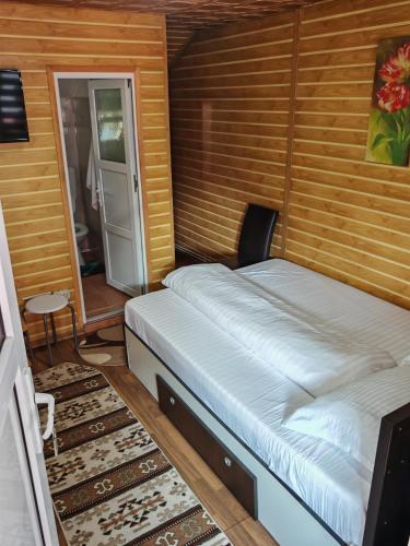 a bedroom with a bed with a wooden wall at Casa Luminita in Brezoi