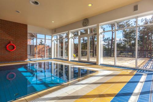 an empty swimming pool in a house with windows at Hotel Kozi Gród in Pomlewo