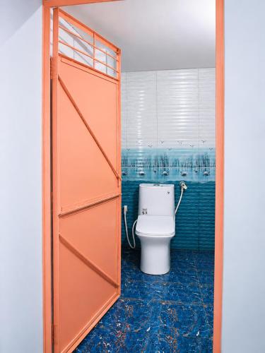 a bathroom with a toilet with an open door at Harshvardhan Lodge in Narsimhapur