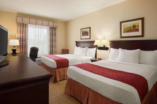 a hotel room with two beds and a desk at Country Inn & Suites by Radisson, Albany, GA in Albany