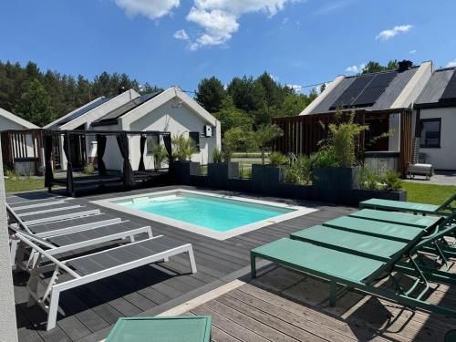 a swimming pool with chaise lounge chairs and a swimming pool at Leśna Polana Domki in Okuninka