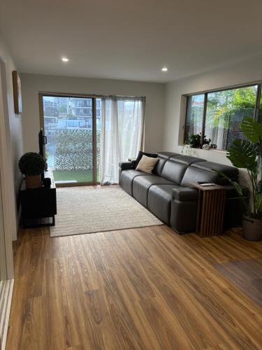 a living room with a black leather couch and wood floors at Surfers 641 in Gold Coast