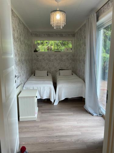 a bedroom with two beds and a chandelier at Idyllic cottage with lake view with 11 beds in Ludvika