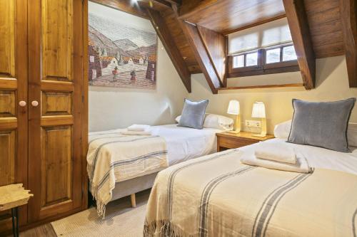 two beds in a room with wooden ceilings at Luderna - Casa con terraza Cuylas in Baqueira-Beret